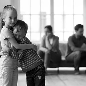 A young girl hugging a boy with their parents in the blurred background, Los Angeles Custody Mistakes During Divorce
