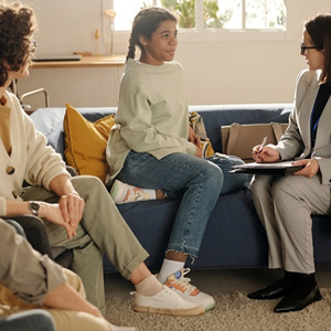 A lawyer consults with two clients on a couch, illustrating a Custody Dispute involving a new partner.