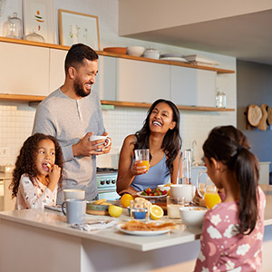 Hispanic family enjoy a cheerful breakfast together in modern kitchen. Mixed race family with two daughters sharing a joyful morning meal around the kitchen island. Multiethnic family having breakfast