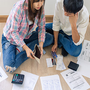 A couple reviewing financial documents and an empty wallet on the floor.